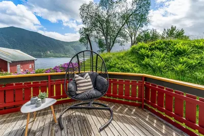 a chair sitting on a deck next to a river at Fjord Lodge direkt am Ufer des Dalsfjord in Lauvstad