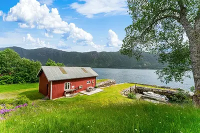 a red house on the shore of a lake at Fjord Lodge direkt am Ufer des Dalsfjord in Lauvstad