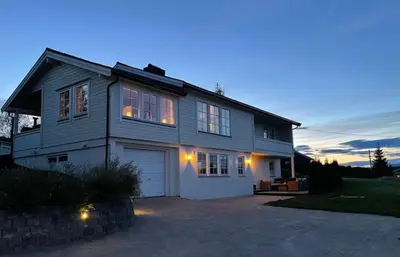 a large house with a garage at dusk at Koselig rom i rolige omgivelser in Rena