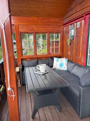 a wooden porch with a table and a couch at Domek Iwony in Molde