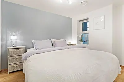 a white bedroom with a large bed and a window at Flott leilighet på Nygårdshøyden in Bergen