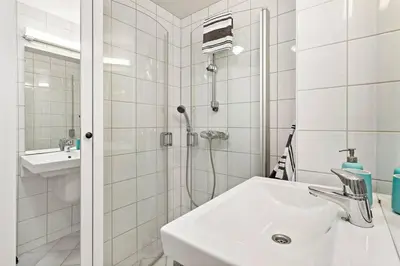 a white bathroom with a shower and a sink at Flott leilighet på Nygårdshøyden in Bergen