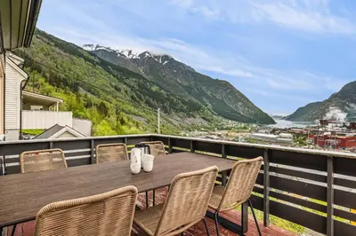 a wooden table and chairs on a balcony with mountains at Odda Living - 3BR & 1BR - A3 in Tokheim