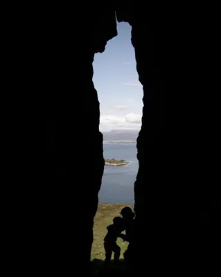 two people standing in a cave looking at the ocean at Birdbox Reksta in Florø