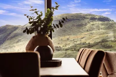 a vase on a table with a view of a mountain at The View - Hodlekve in Sogndal
