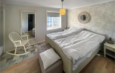 a bedroom with a bed and a chair and a mirror at 4 Bedroom Cozy Home In Svorkmo in Brattli