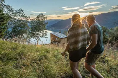 a man and woman standing on a hill looking at the view at Sørheim FjordPanorama in Skjolden