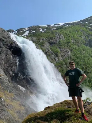 a man standing in front of a waterfall at Sørheim FjordPanorama in Skjolden