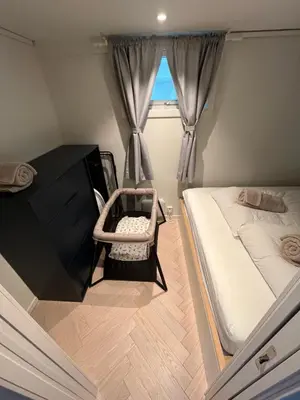 a small bedroom with a bed and a chair at Entire renovated apartment from 1780 with Kitchen, Bath, Bedroom, and Living Room in Skuteviken in Bergen