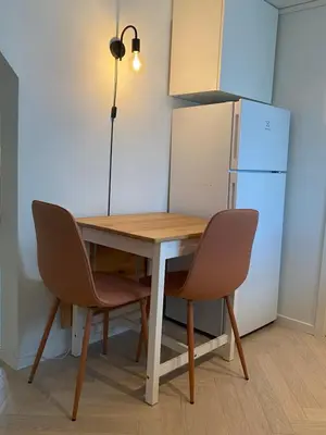 a kitchen table with two chairs and a refrigerator at Entire renovated apartment from 1780 with Kitchen, Bath, Bedroom, and Living Room in Skuteviken in Bergen