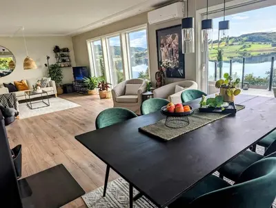 a living room with a black table and green chairs at Nyoppusset hus med utsikt. in Steinkjer