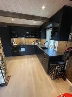 a large kitchen with black cabinets and a sink at Stugu - Koselig hytte med sentral beliggenhet in Åker