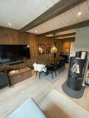 a living room with a table and a tv at Stugu - Koselig hytte med sentral beliggenhet in Åker