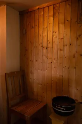 a room with a wooden wall with a toilet and a chair at Osloveien 6 in Røros