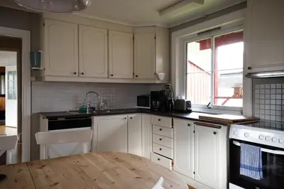 a kitchen with white cabinets and a wooden table at Osloveien 6 in Røros