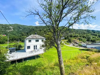 a white house on a hill with a tree at Holiday Home Sjøtun by Interhome in Hyllestad