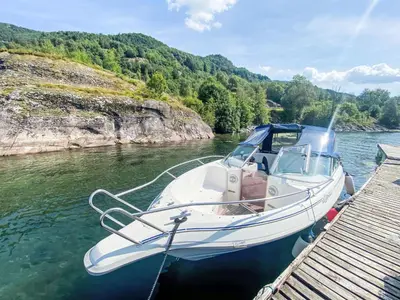 a white boat docked at a dock in the water at Holiday Home Sjøtun by Interhome in Hyllestad
