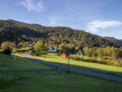 a road in a field with a house and a mountain at Chalet Heggland Huset by Interhome in Heggland