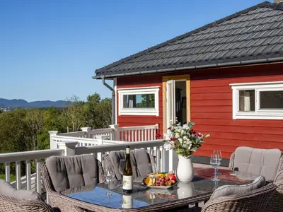 a table on the deck of a red house at Chalet Heggland Huset by Interhome in Heggland