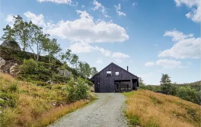 a black barn on a hill with a dirt road at Beautiful Home In Jøsenfjorden in Gullingen