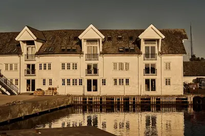 a large white building next to a body of water at Bekkjarvik Gjestgiveri in Bekkjarvik