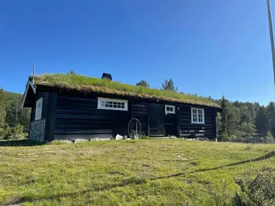 a log cabin with a grass roof on a field at Maurtua - cabin in lovely surroundings in Kvam