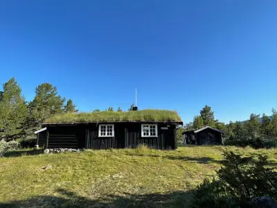 an old house with a grass roof on a field at Maurtua - cabin in lovely surroundings in Kvam