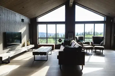 a living room with couches and a tv and large windows at Chill cabin - fantastic view and nice hiking area in Aurdal