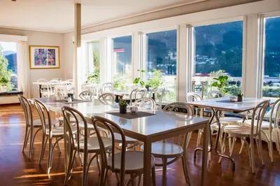 a dining room with tables and chairs and windows at Førde Pensjonat in Førde
