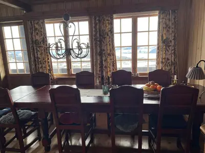a dining room with a table and chairs and windows at Bjødnabakkvegen 22C in Beitostøl