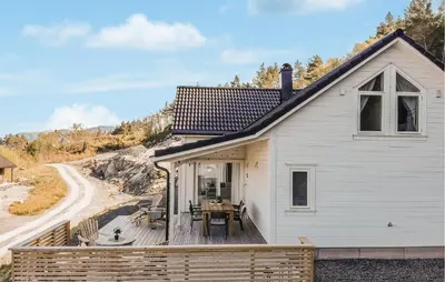 a white house with a wooden deck with a table at 4 Bedroom Amazing Home In Skånevik in Skånevik
