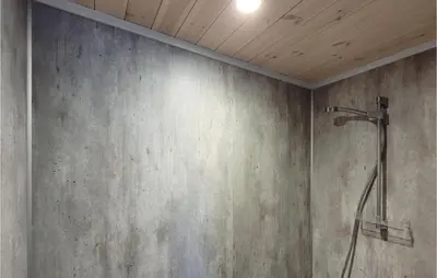 a shower in a bathroom with a concrete wall at 4 Bedroom Amazing Home In Skånevik in Skånevik