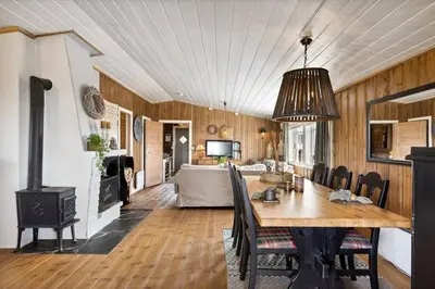a dining room with a table and a living room at Cozy and comfortable cabin in the center of Sjusjøen with a large terrace in Ringsaker