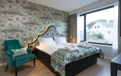 a bedroom with a bed and a green chair at Thon Hotel Fosnavåg in Fosnavåg