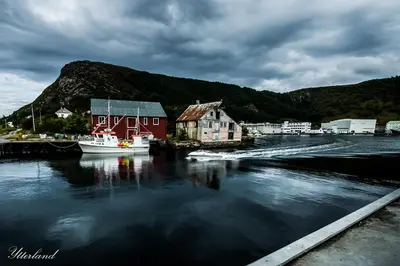 a river with houses and a boat in the water at Thon Hotel Fosnavåg in Fosnavåg