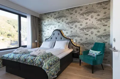 a bedroom with a bed and a green chair at Thon Hotel Fosnavåg in Fosnavåg
