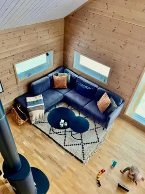 a living room with a blue couch and a rug at Cozy cabin on Sjusjølia by the trail network sauna in Ringsaker