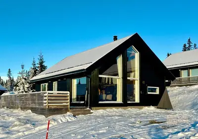 a black house in the snow with snow at Cozy cabin on Sjusjølia by the trail network sauna in Ringsaker