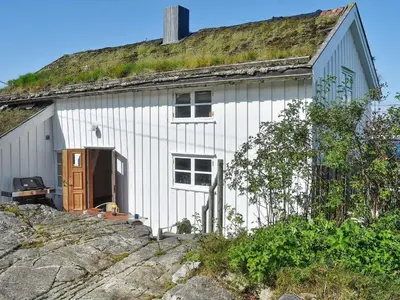 a white house with a grass roof with a door at 7 person holiday home in Averøy-By Traum in Averoy