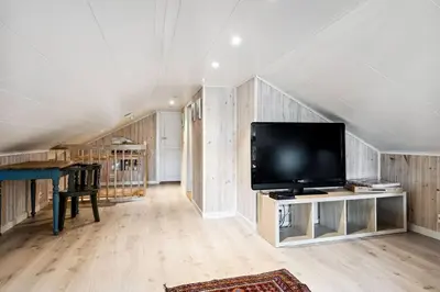 a living room with a flat screen tv in a attic at Koslig hytte ved Grimsdalen in Dovre
