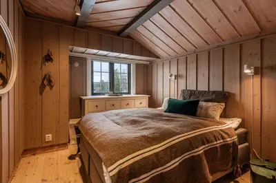 a bedroom with a bed in a room with wooden walls at Large cabin with spectacular views in Geilo in Geilo
