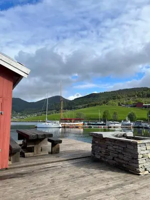 a dock with a bench and boats in the water at Handelsmannens hus ved Otnesbrygga, Valsøyfjord in Otnes