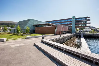 a building next to a body of water next to a building at Quality Hotel Ulstein in Ulsteinvik