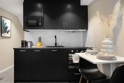 a kitchen with black cabinets and a white counter top at Renovated jan 24 - Queen beds - Behind Bryggen in Bergen