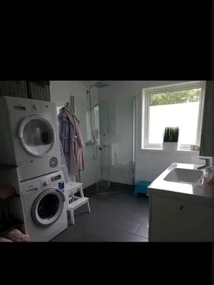 a bathroom with a washing machine and a sink at Hus ved sjøen in Bakken