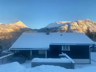a house covered in snow with mountains in the background at 2 mannsbolig i Hemsedal sentrum, nær skianlegget - 3 sov og 7 sengeplasser in Hemsedal