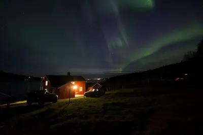 a house with a car parked in a field at night at Edvinstua Solbakken Feriehus in Fevåg