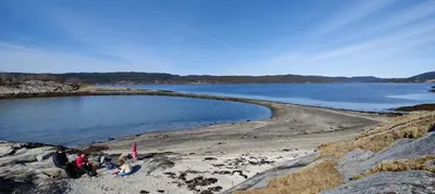 a group of people standing on a beach near the water at Strandstua Solbakken Feriehus in Fevåg