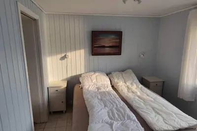 a bed in a bedroom with a picture on the wall at Apartment Solbakken Feriehus in Fevåg