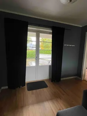 a living room with a large window with black curtains at Stue, soverom og bad in Åmot